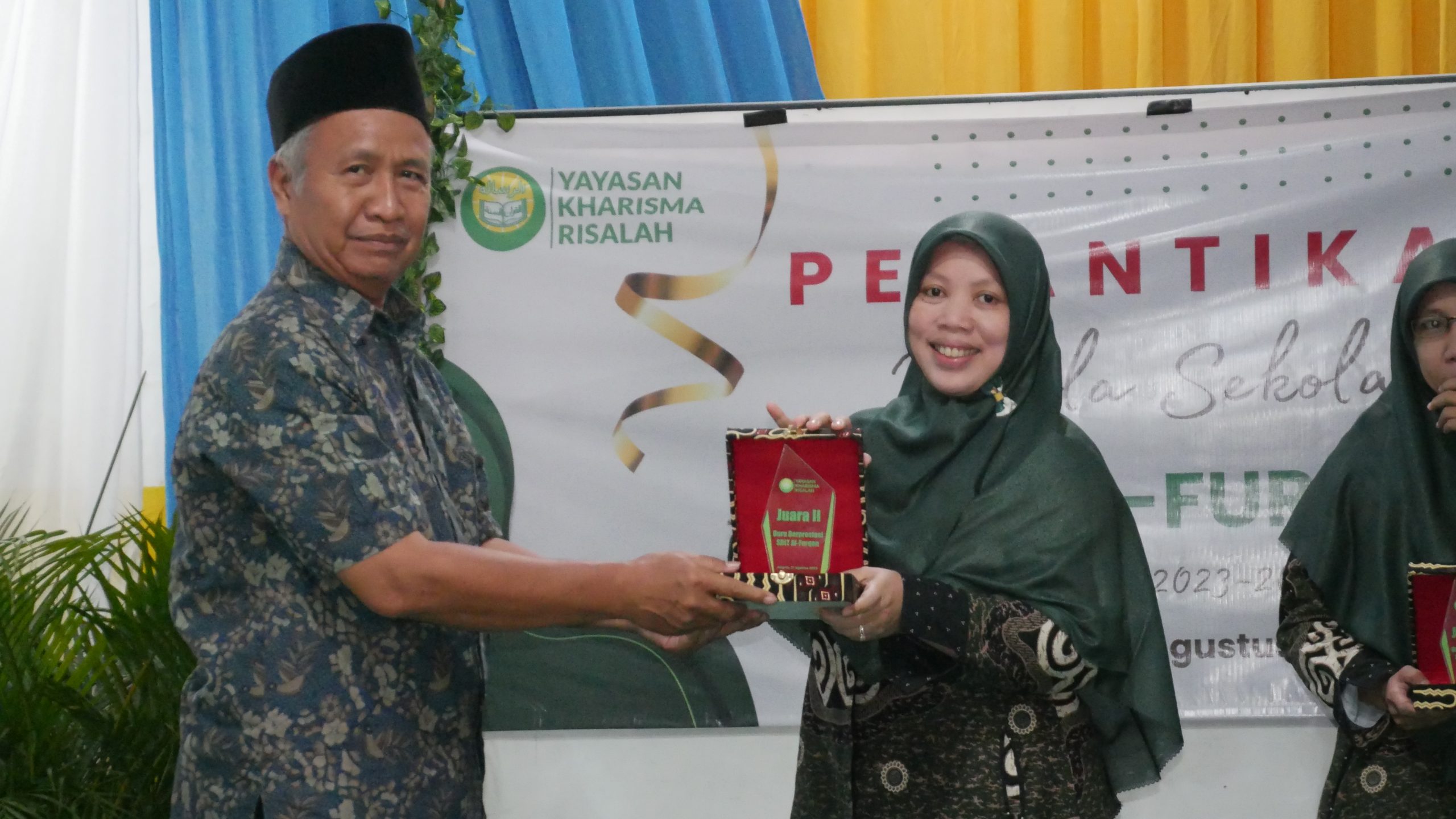 Pemberian plakat penghargaan guru favorit SDIT Al-Furqon diwakili bendahara Yayasan Kharisma Risalah kepada Ibu Setiawati